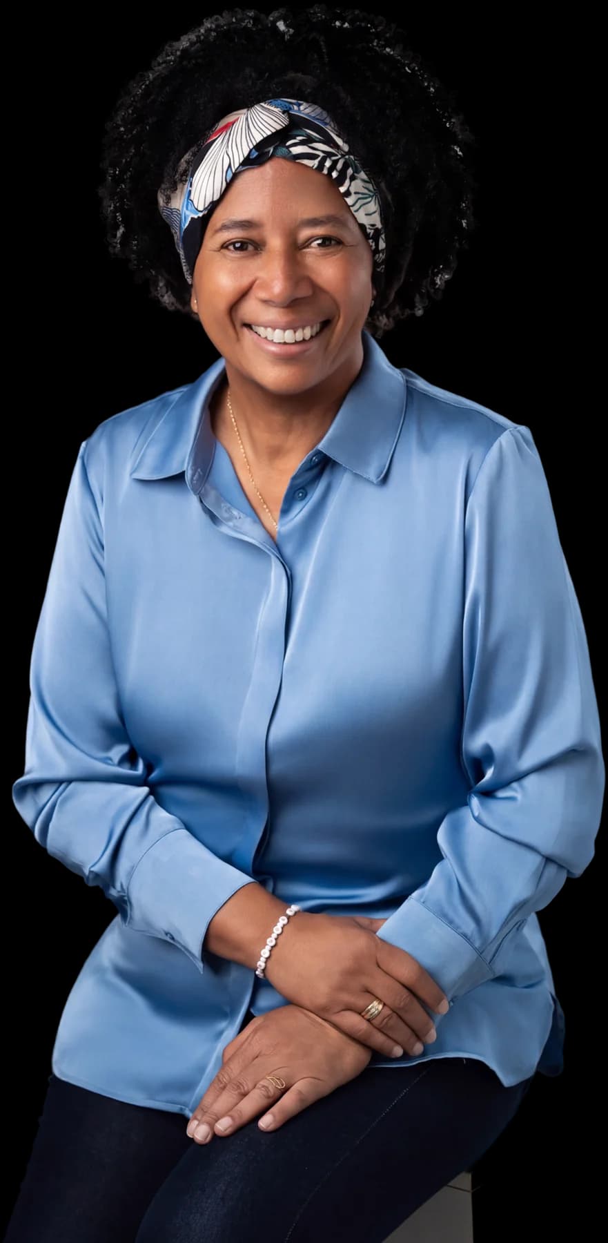 Silvia Cristina sentada, de camisa azul, em foto de estúdio.